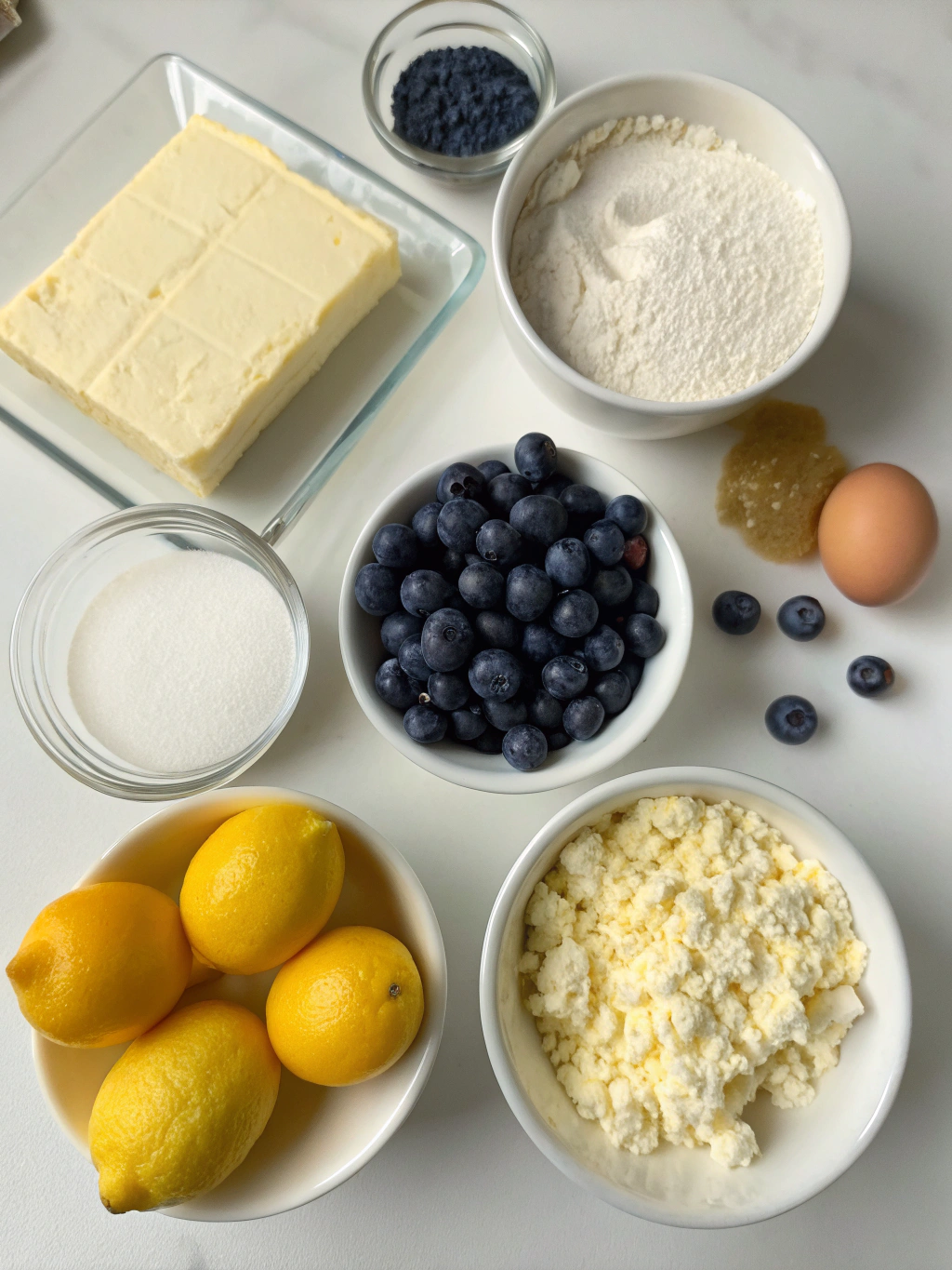 Ingredients for Lemon Blueberry Cheesecake Bars laid out on a marble countertop